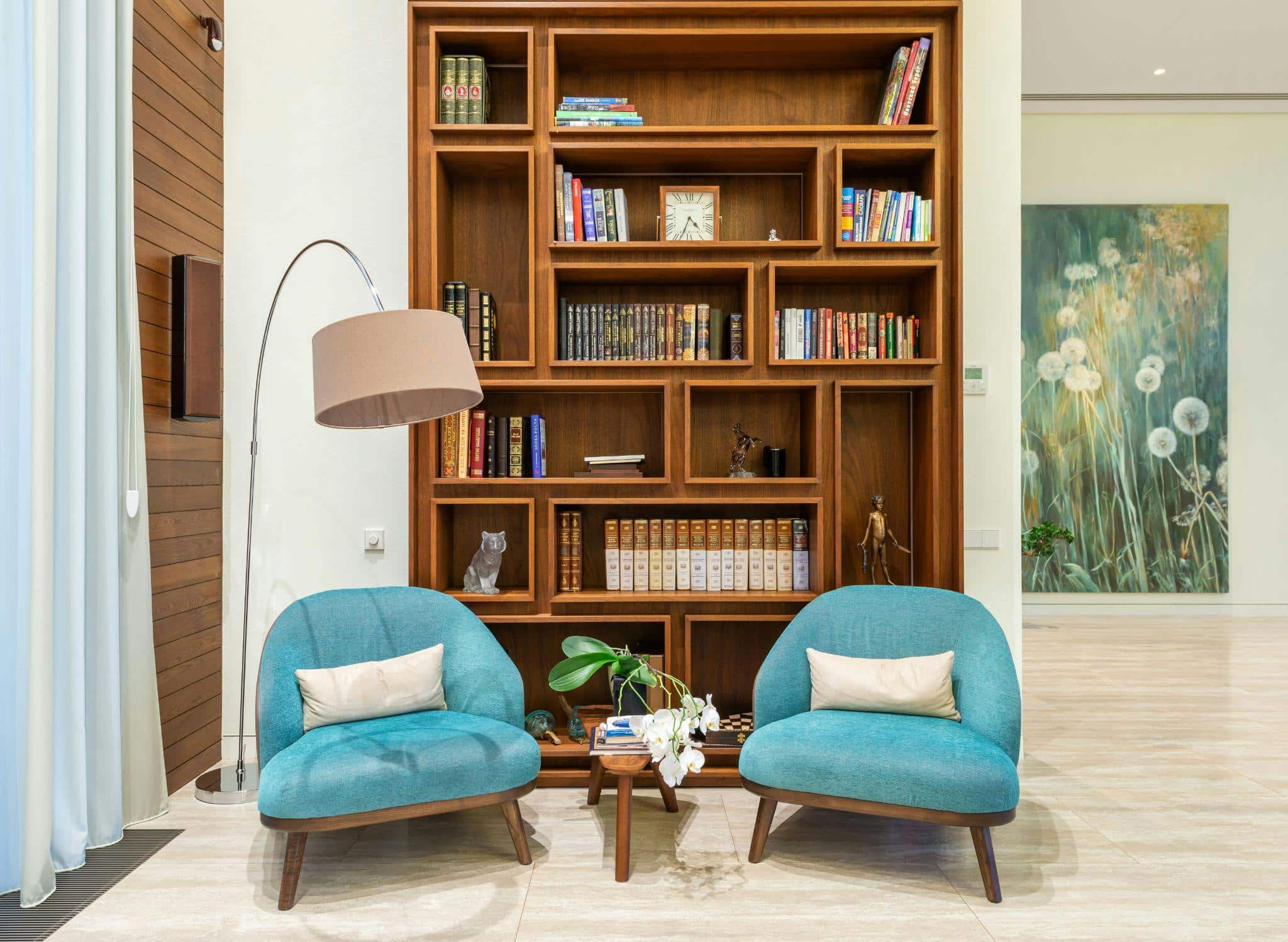 Living room with cozy chairs, lamp, and wooden bookcase