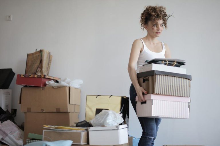 Free A young woman carrying boxes during a move into a new apartment, surrounded by packed belongings. Stock Photo