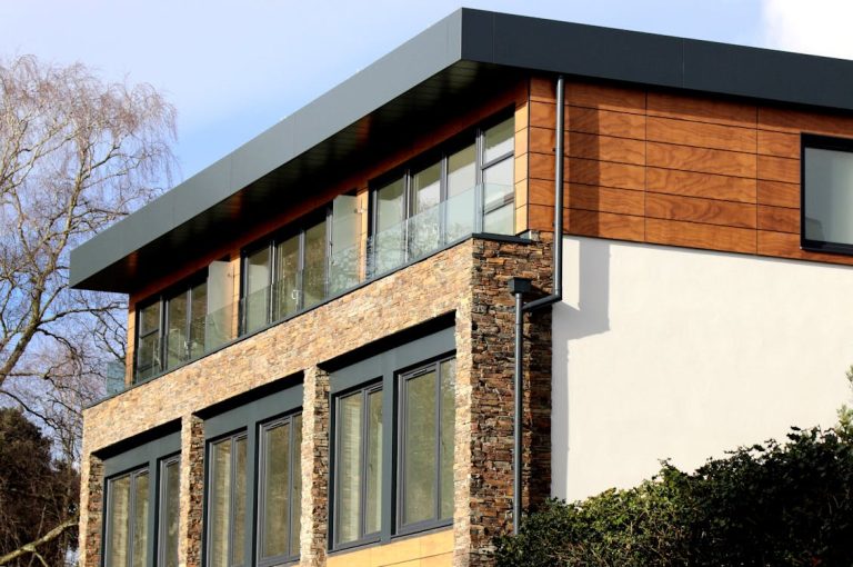 Free Contemporary house in Poole featuring a striking mix of stone and wood facade with large windows. Stock Photo