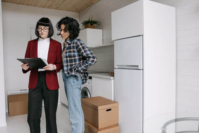 Free Two women reviewing documents in a kitchen amid moving boxes. Stock Photo