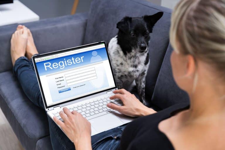 A woman registering online for an ESA letter while her dog sits beside her on the couch