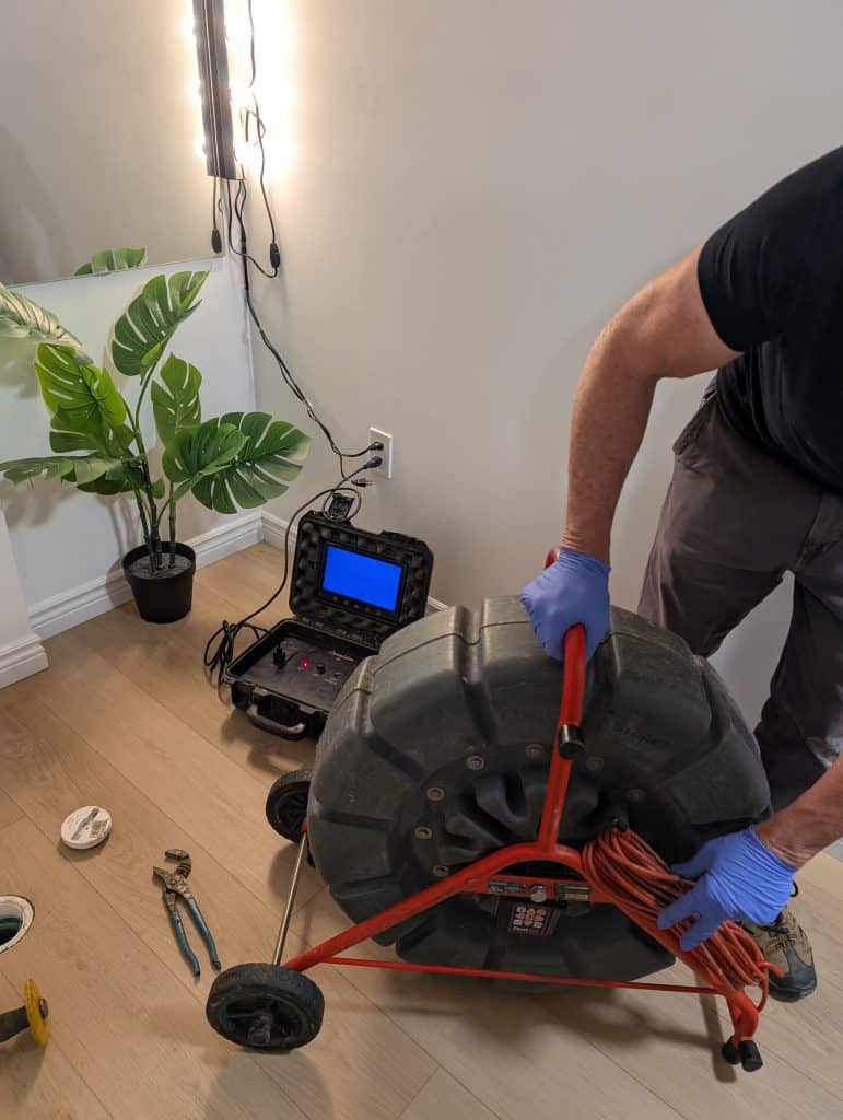A man operates a wheel to roll a large tire across a surface