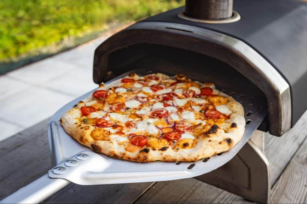 putting pizza into an outdoor wood-fired oven”