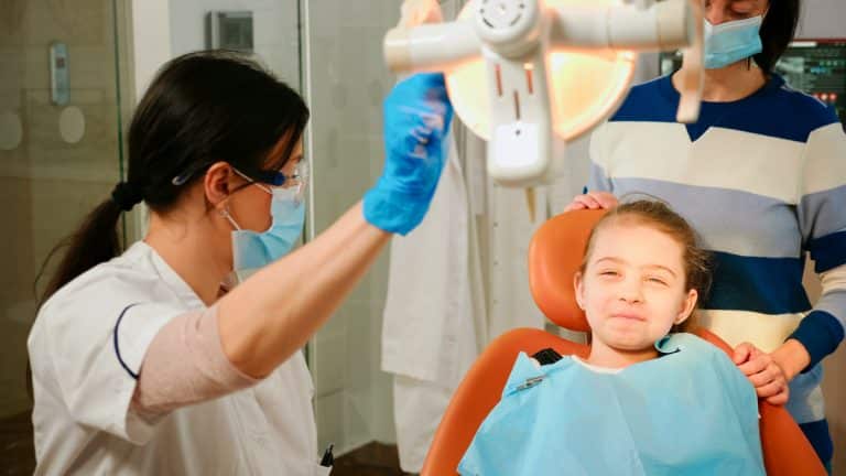 Woman stomatologist technician lighting the lamp for examining little patient