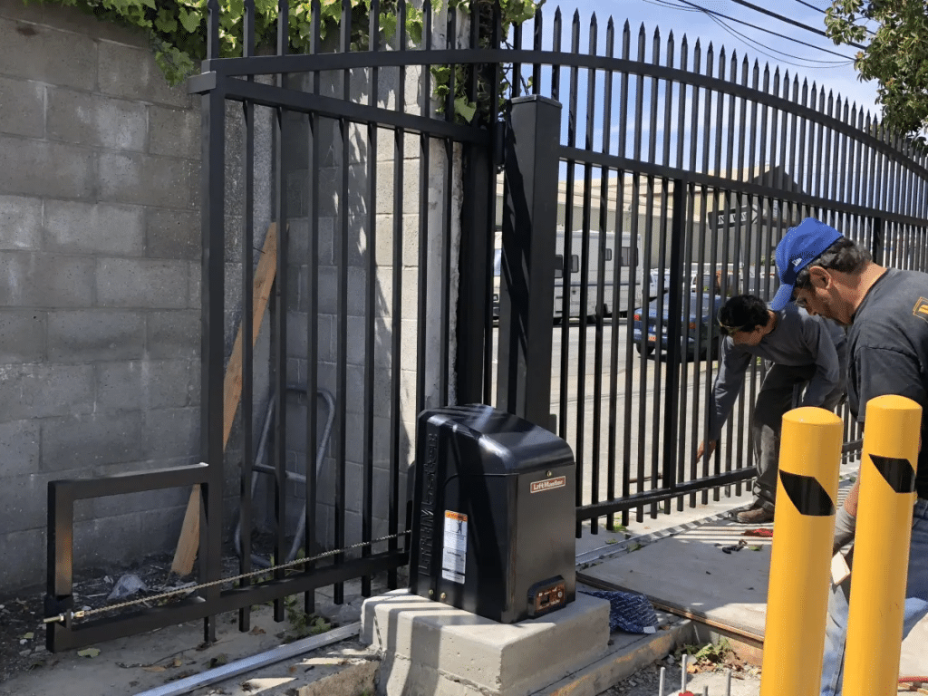 Technicians inspecting and adjusting a motorized sliding gate system to prevent breakdowns and ensure smooth operation