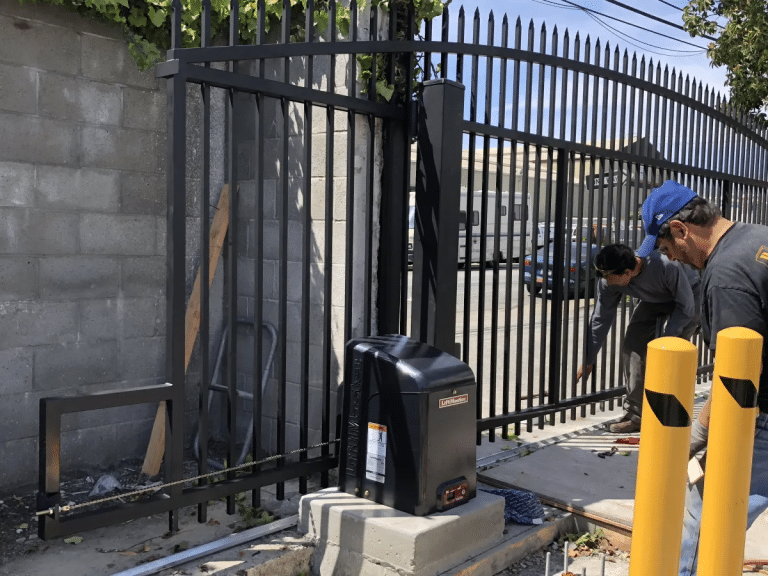 Technicians inspecting and adjusting a motorized sliding gate system to prevent breakdowns and ensure smooth operation