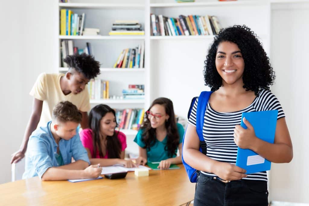 Mexican female student with group of international students at library of university