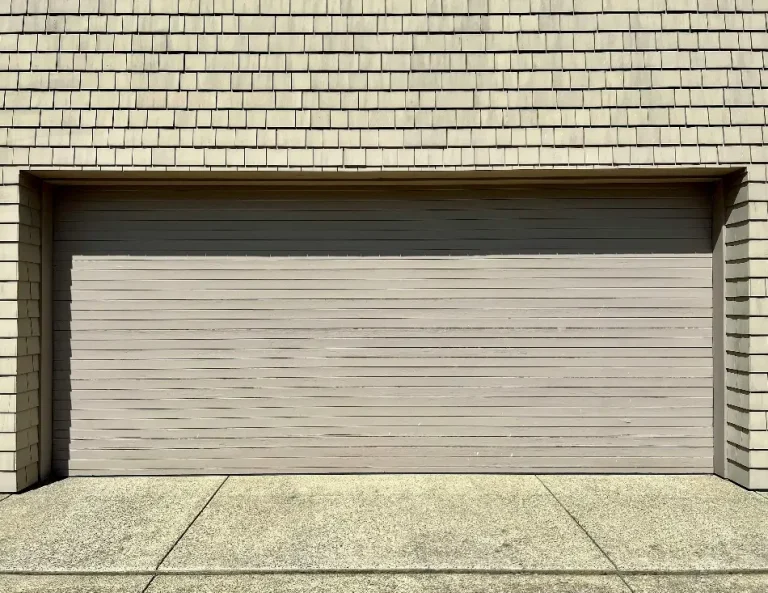 Wooden garage door with vertical paneling set in a shingle-clad exterior wall