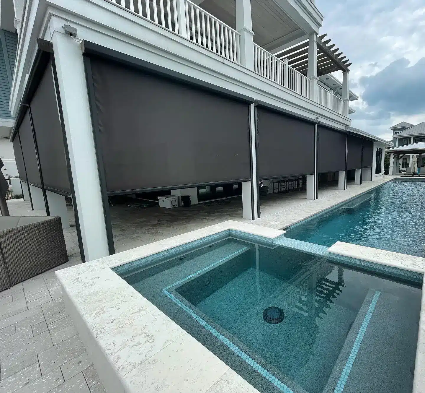 Modern outdoor pool with pergola and automatic shades on stone patio