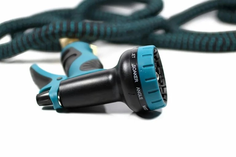 Blue and black garden hose nozzle with settings, coiled hose in background, on white surface