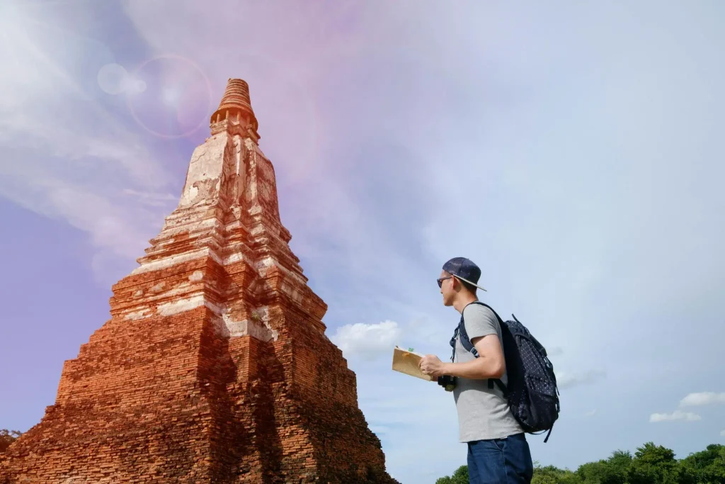 Man with backpack examining ancient brick stupa in bright outdoor setting