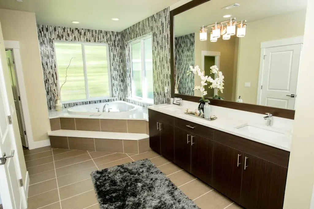 Modern bathroom with large mirror, dark wood vanity, and corner bathtub under natural light