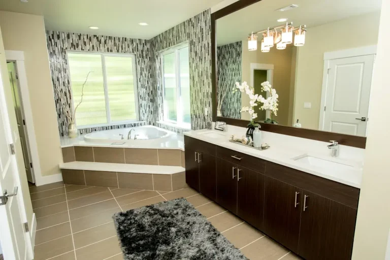 Modern bathroom with large mirror, dark wood vanity, and corner bathtub under natural light
