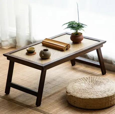 Low wooden tea table with bonsai and cups on tatami mat in sunlit room