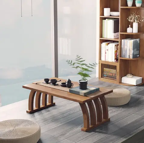 Tea set on wooden table in bright room with floor cushions and bookshelves