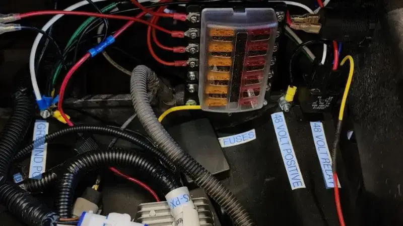 Electrical panel with colorful wires and fuses in a dimly lit setting