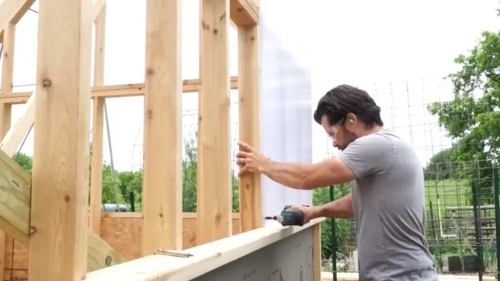 A person is adding sheets on wooden beam during construction.