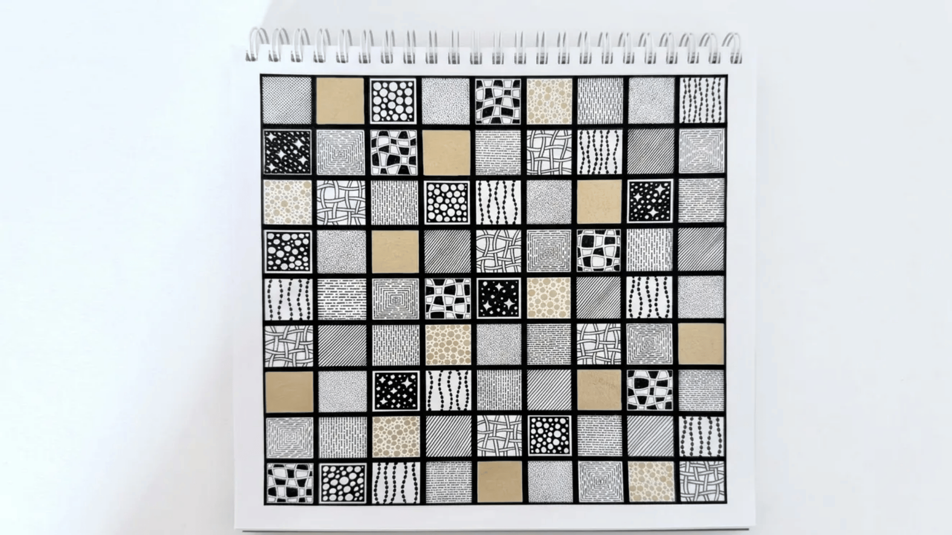 A sketchbook page filled with neat black-and-white zentangle-style pattern squares arranged in a clean grid layout.