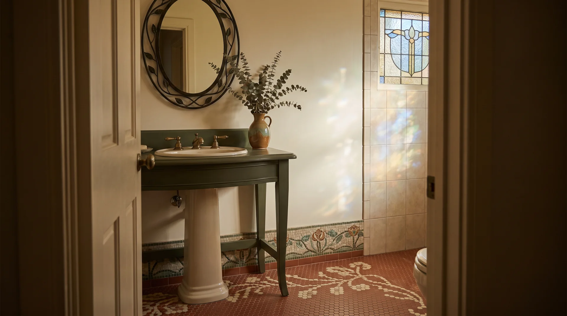 Art Nouveau bathroom with a dark wood vanity, an oval carved mirror, patterned floor tiles, and a stained glass window.