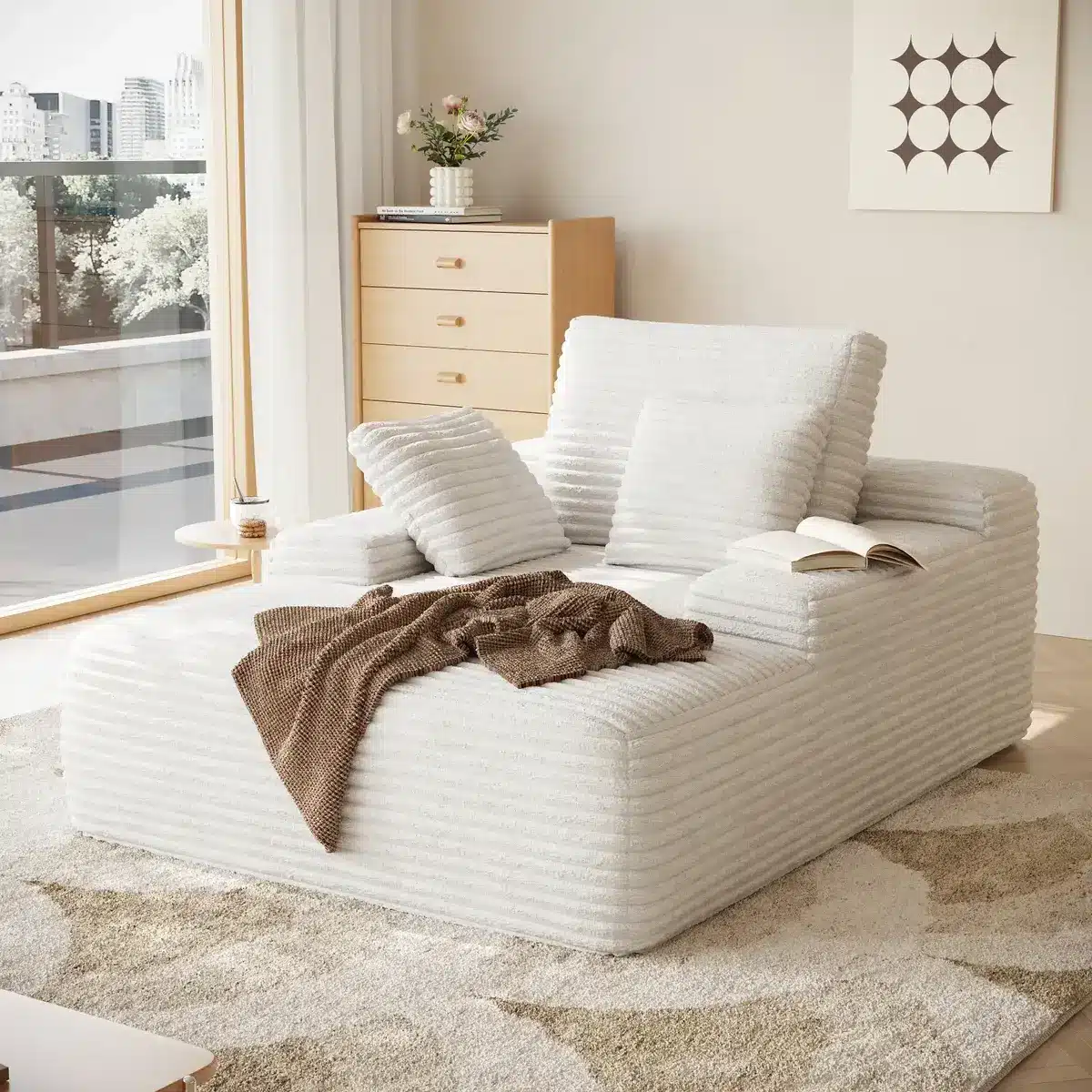 Contemporary living room with plush white sectional sofa and brown throw blanket near large window