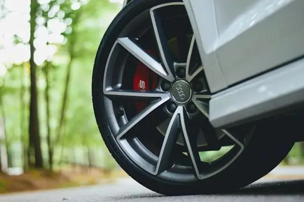 Close-up of a car wheel with silver alloy rims on a forest road