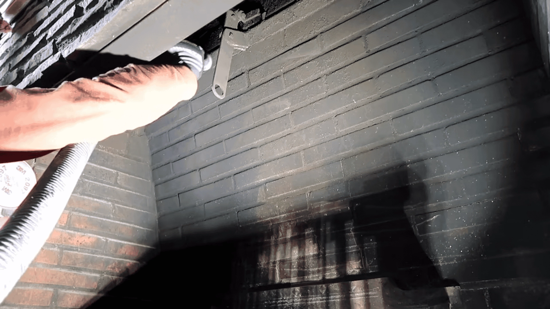 close-up-of-a-person-using-a-vacuum-hose-to-clean-soot-and-ash-from-a-brick-fireplace-interior