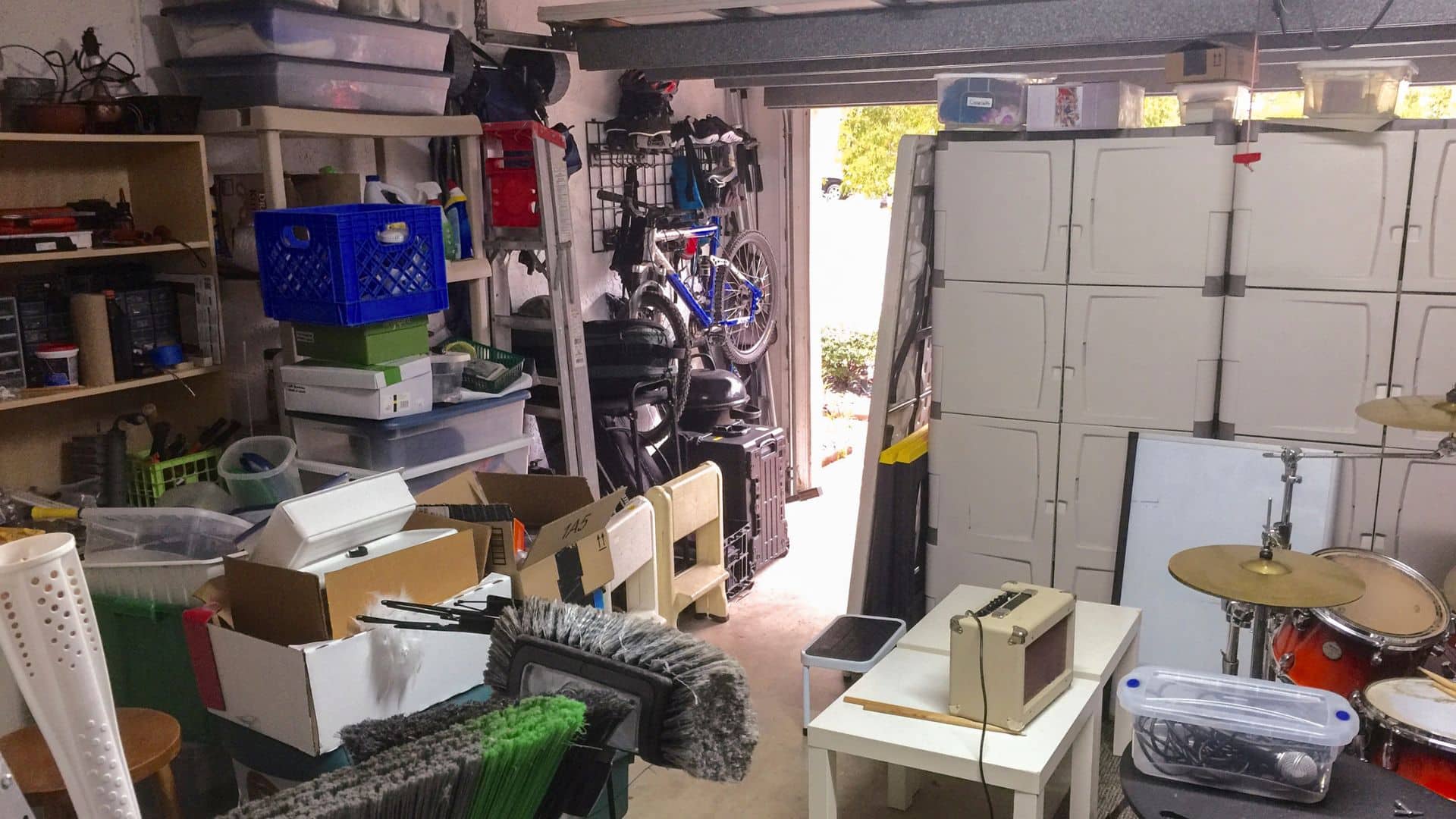Cluttered garage with boxes, shelves, bikes, and tools showing before setup, ideal example for how to organize garage and maximize storage space