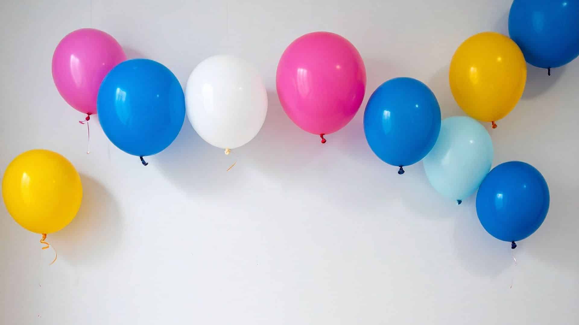 Colorful balloons spaced along wall, showing how to hang balloons on wall using simple adhesive methods for clean, festive decoration