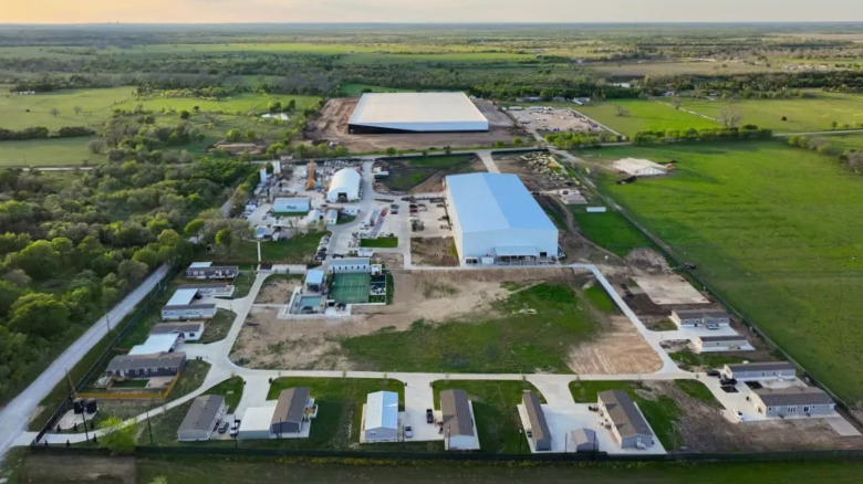 Hyper-realistic construction scene of Elon Musk’s Austin compound being built, modern luxury estate under construction in a wealthy Texas neighborhood.