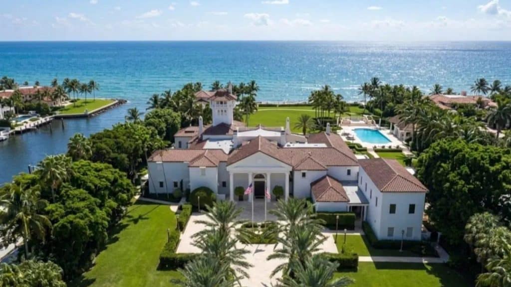 Elon Musk’s Miami mega mansion featuring a massive waterfront luxury estate, sleek modern architecture, floor-to-ceiling glass walls, palm trees, private driveway, infinity pool, yacht dock.