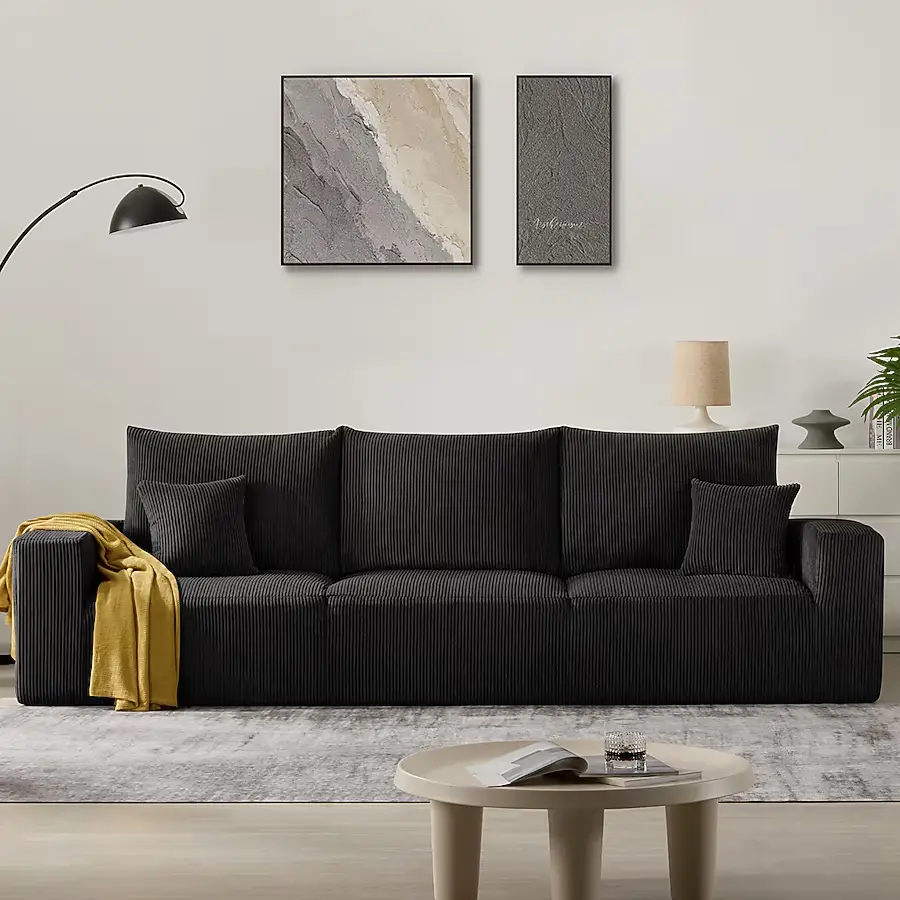 Black corduroy sofa with yellow throw in modern living room with abstract wall art and floor lamp