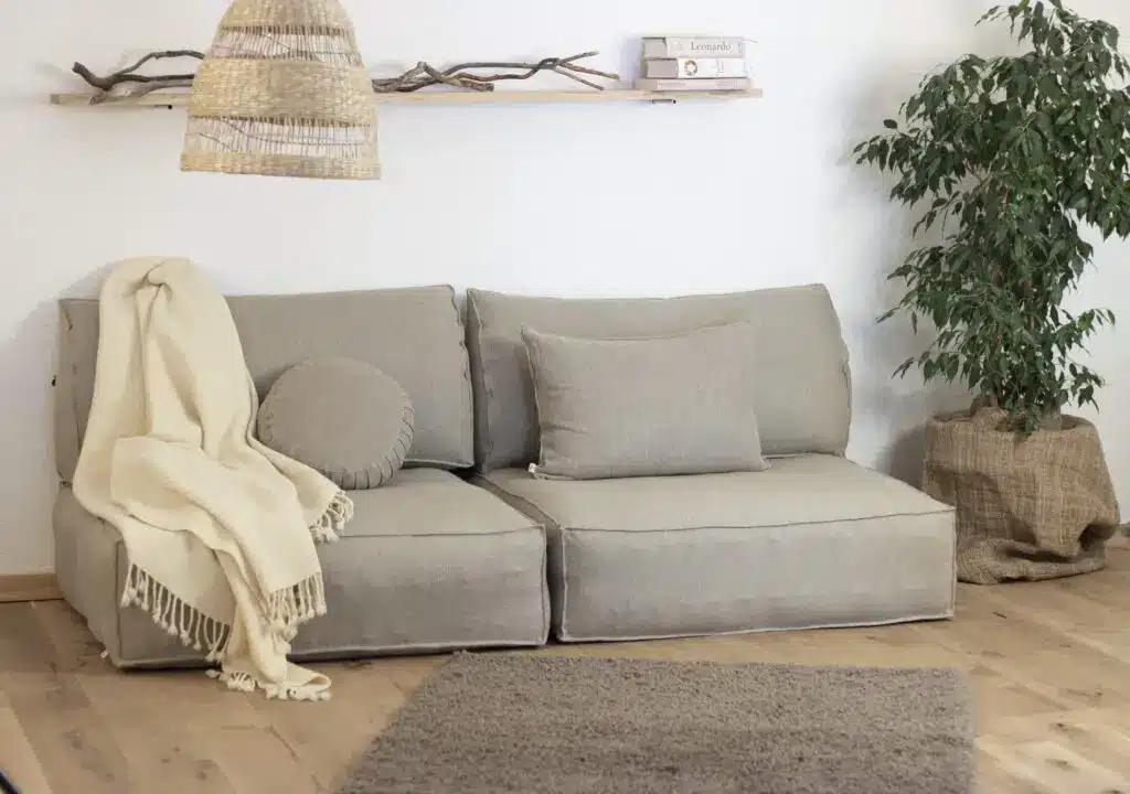 Gray upholstered sofa with beige throw blanket in cozy living room setting
