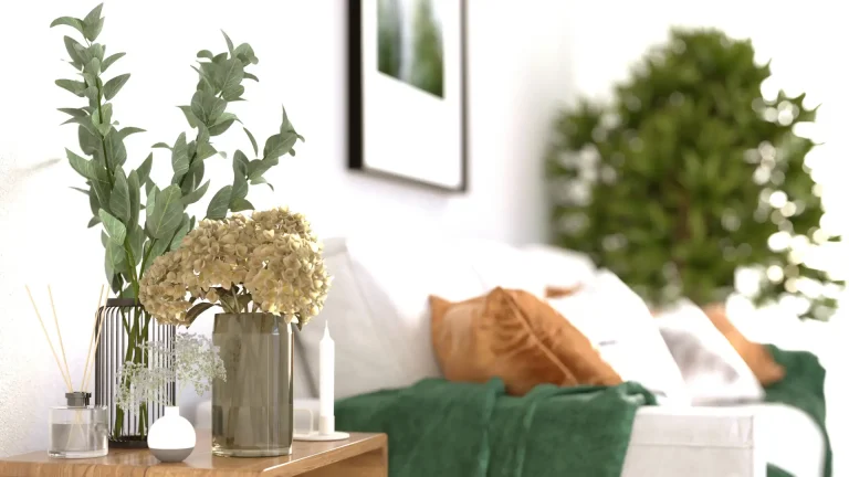 Vase of flowers and eucalyptus on wooden table beside white sofa with orange pillows