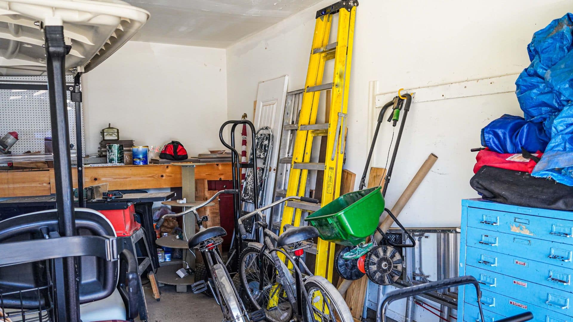 Messy garage with bikes, ladder, tools, and storage clutter showing before organizing, useful visual for how to organize garage efficiently