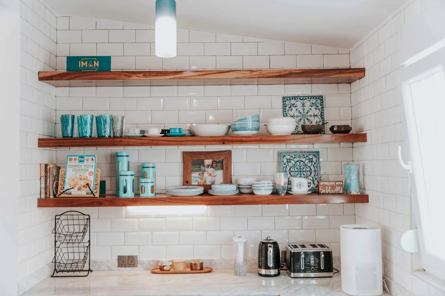 Wooden shelves with turquoise kitchenware and decor against white tiled wall in bright kitchen