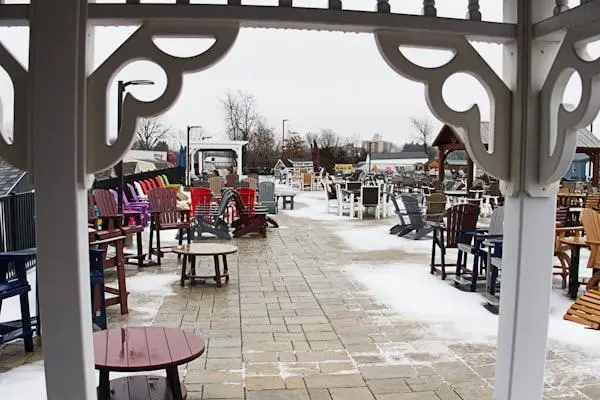 Outdoor furniture display area with colorful chairs and tables on a snowy patio under overcast sky