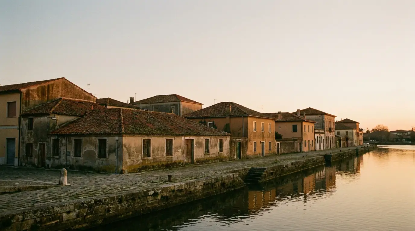 Historic buildings with tiled roofs along waterfront at sunset reflecting on calm water