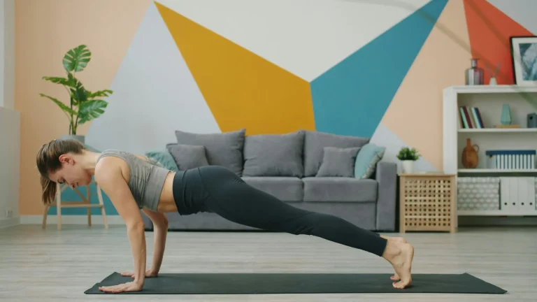 Woman practicing yoga plank pose on mat in modern living room with colorful geometric wall