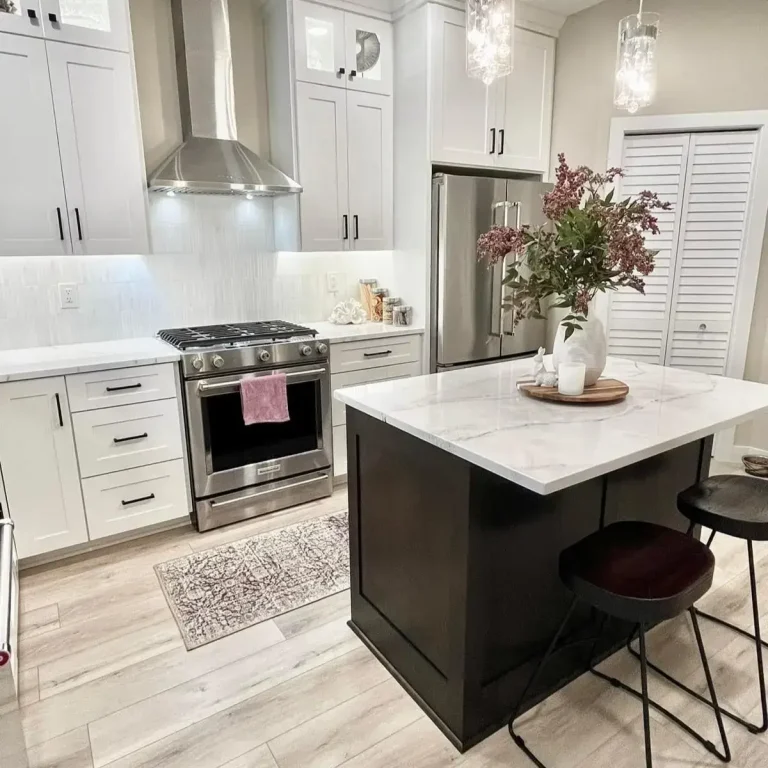 Modern kitchen with white cabinets, stainless steel appliances, and a marble island with flowers