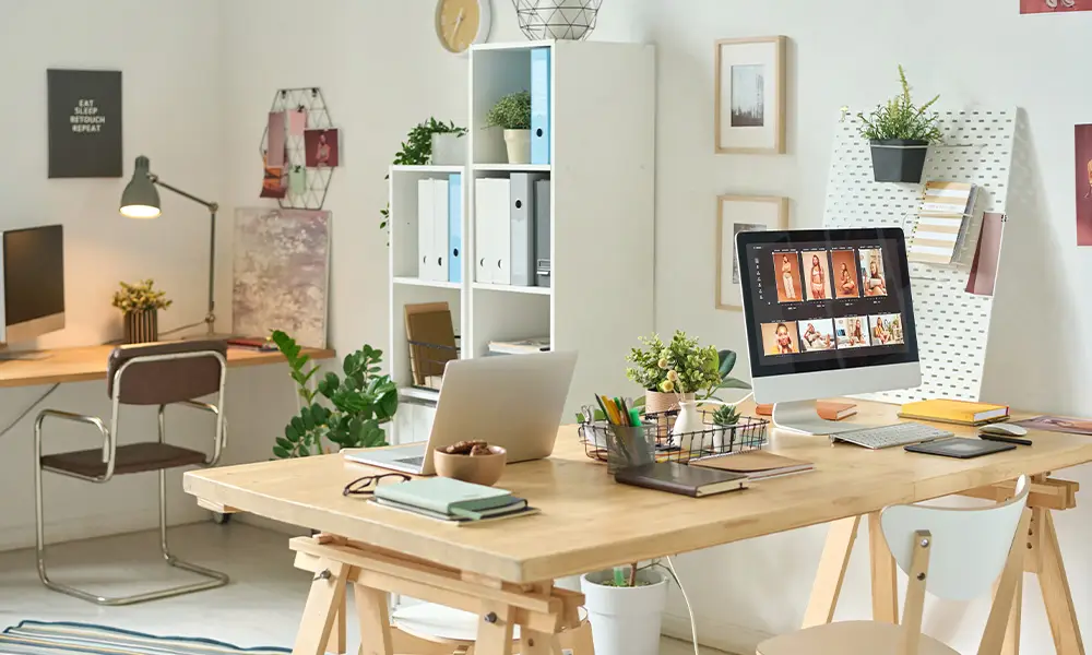 Modern home office with computers on wooden desks and potted plants under bright lighting