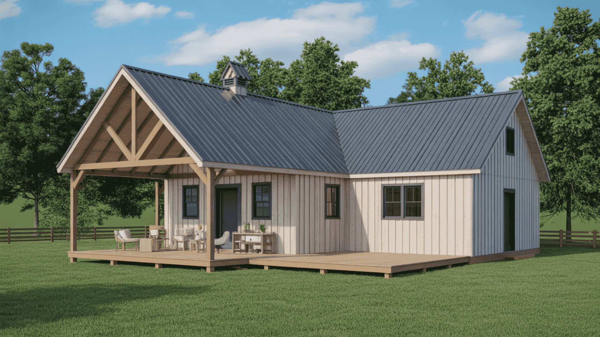 An L-shaped, one-story barndominium house with light siding, a dark metal roof, and a spacious wooden porch on a green lawn.