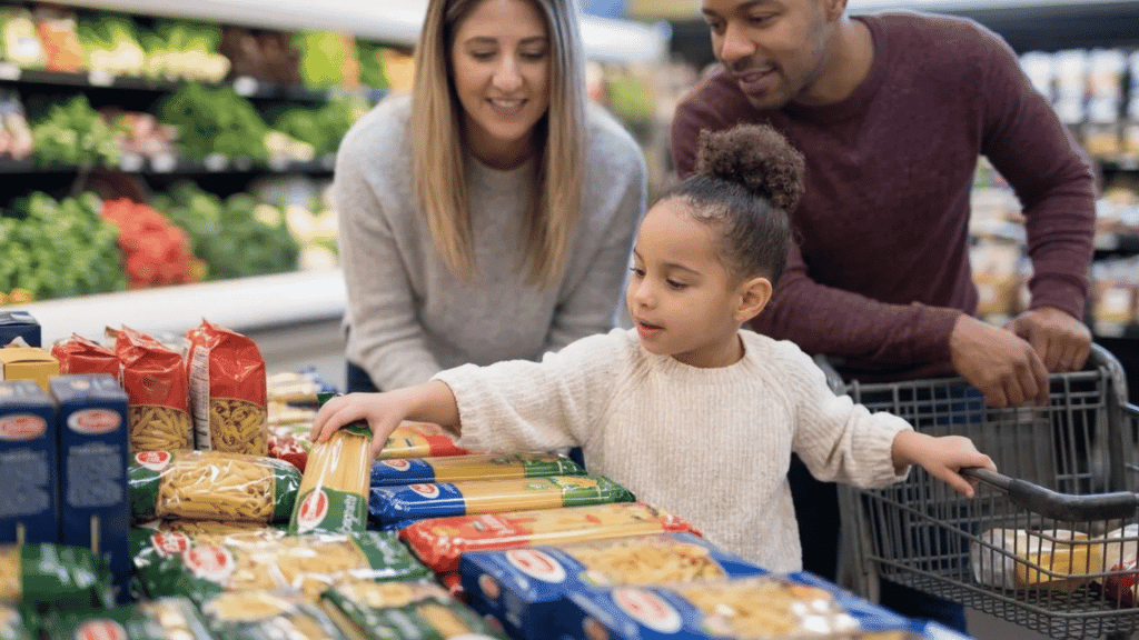 Family shopping together in a grocery store while choosing pantry staples and everyday food items.