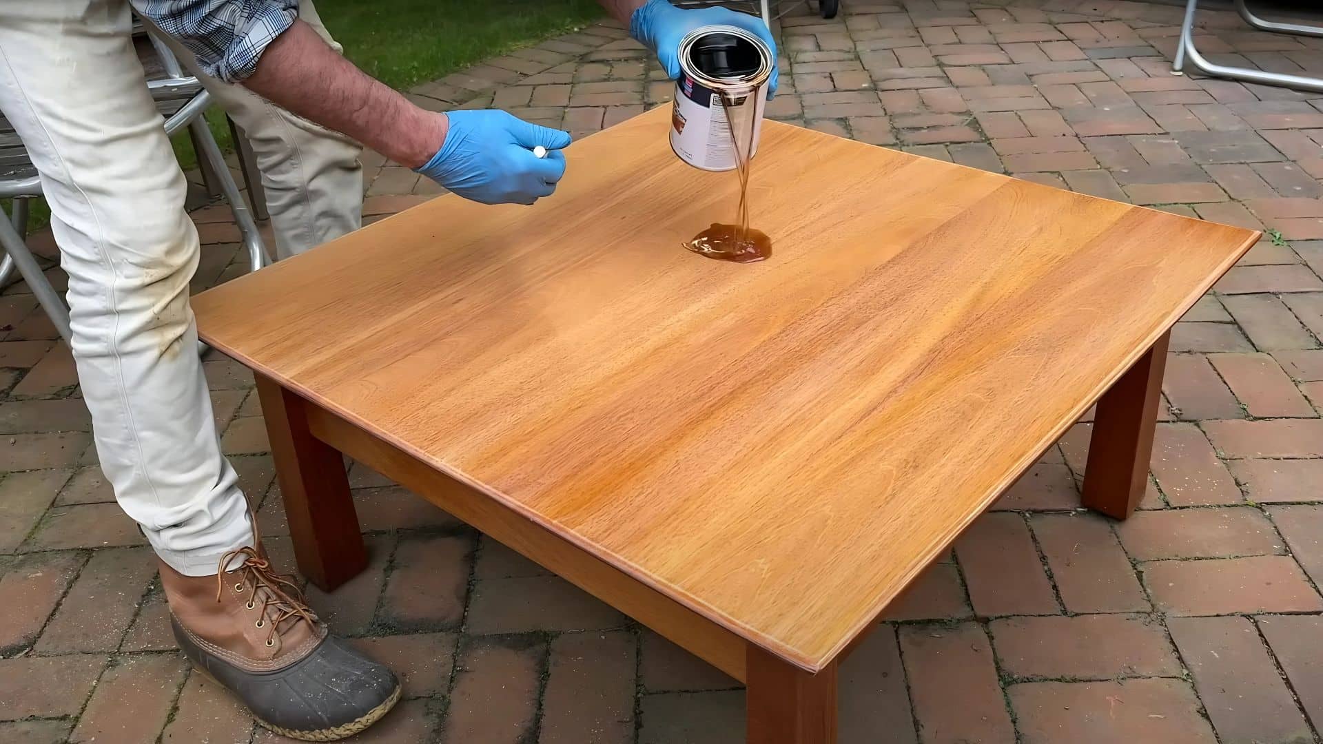 A hand using a foam roller to smoothly apply the first coat of clear gloss varnish onto a wooden surface.