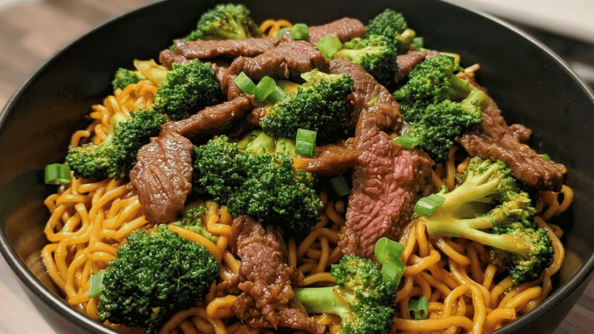 Beef and broccoli noodles tossed in a savory sauce with tender beef, fresh broccoli, and green onions.