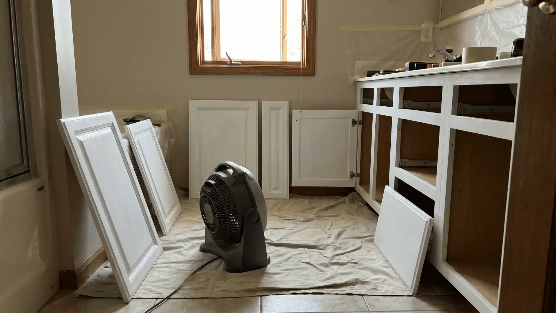 Clean bathroom cabinet parts drying with airflow from a nearby fan.