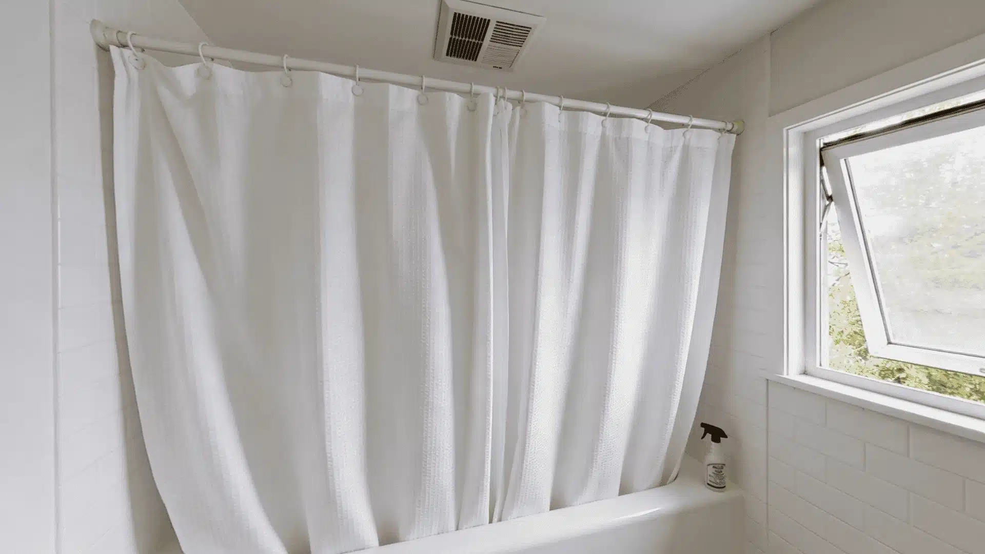clean shower curtain beside a bathtub with unlabeled cleaning supplies on a bathroom counter