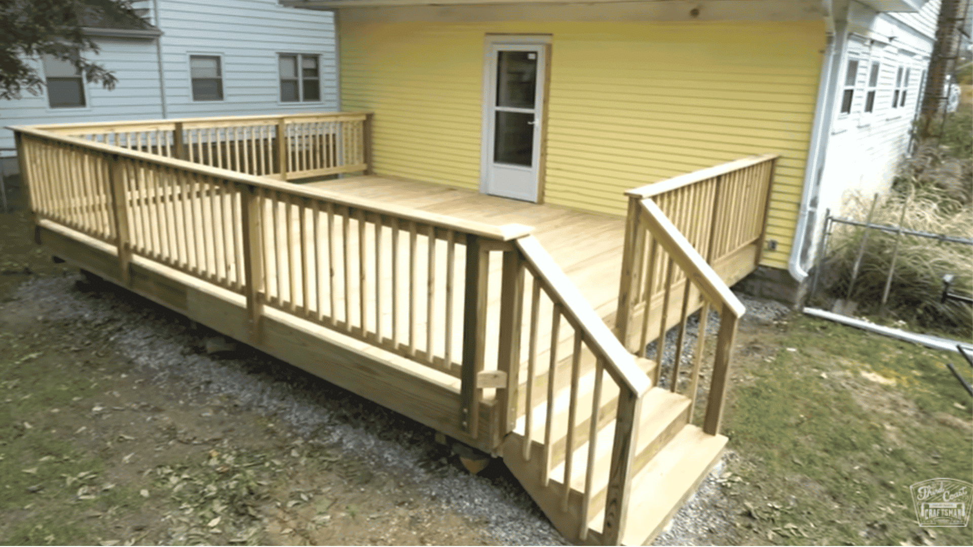 Completed wooden deck with railing, stairs, and surrounding area visible from an angle