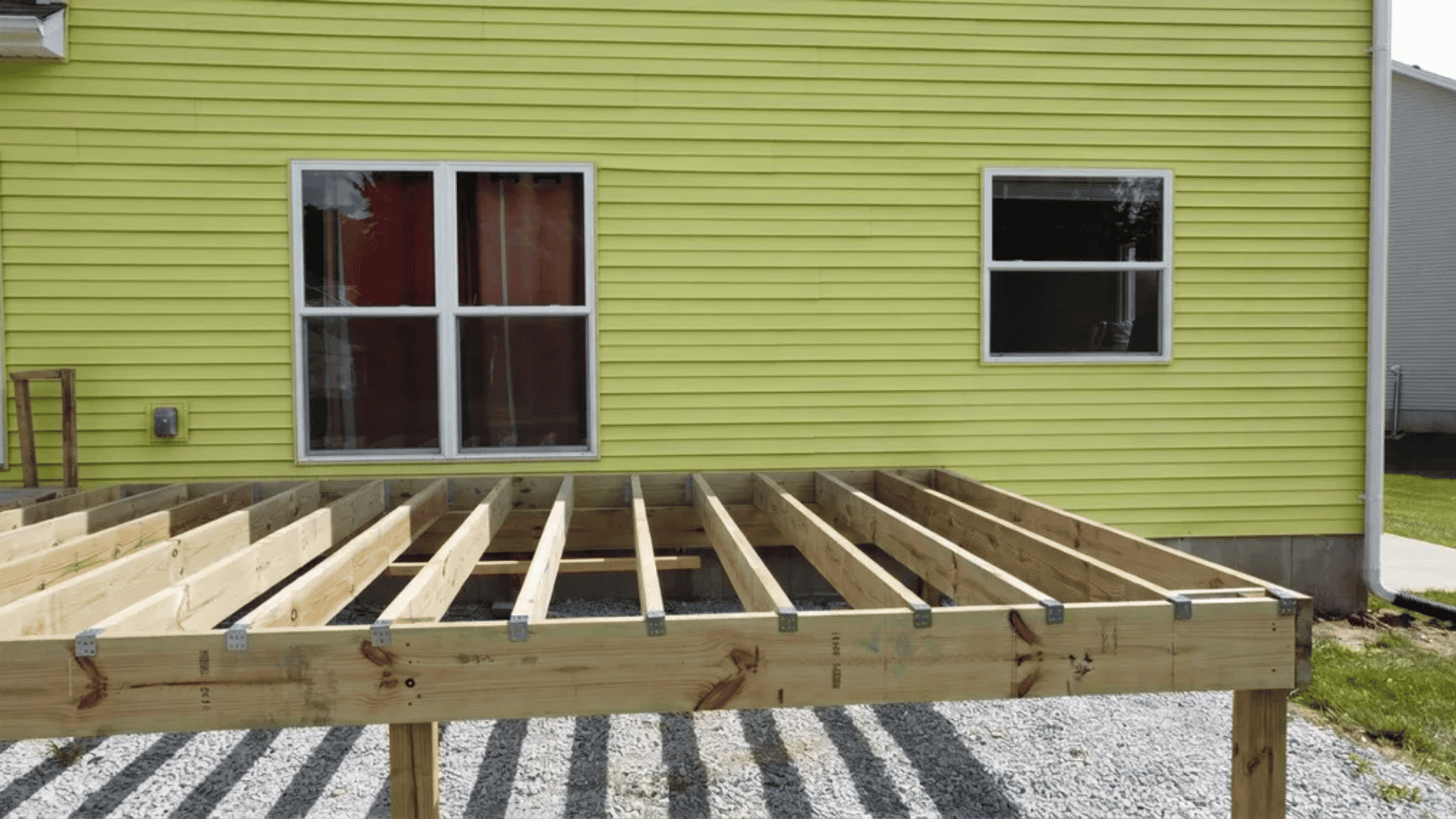 Deck frame installed with evenly spaced joists ready for decking boards, viewed from the backyard.