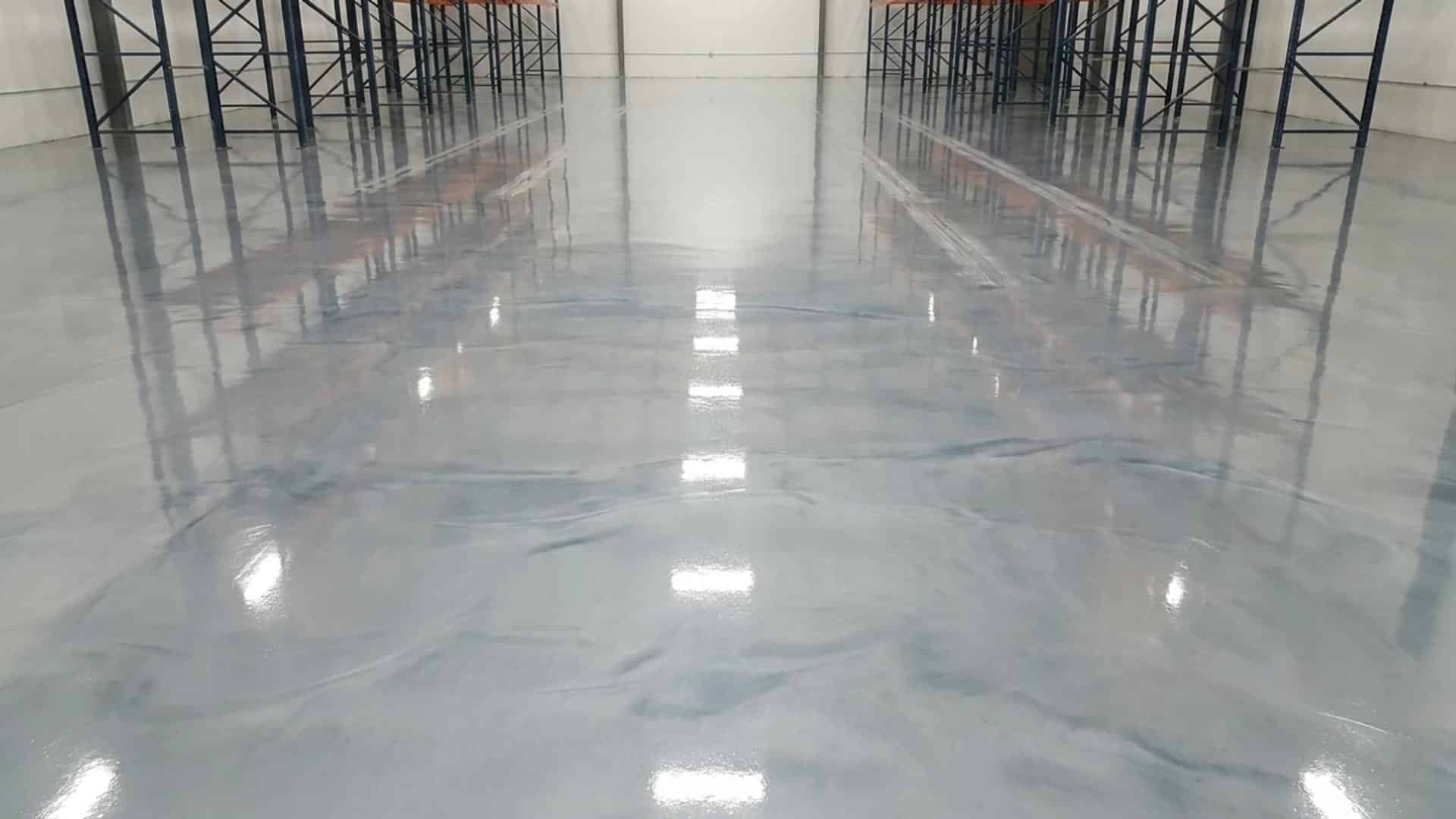 High-gloss, seamless gray epoxy garage floor coating resisting heavy wear, oil stains, and tire marks.