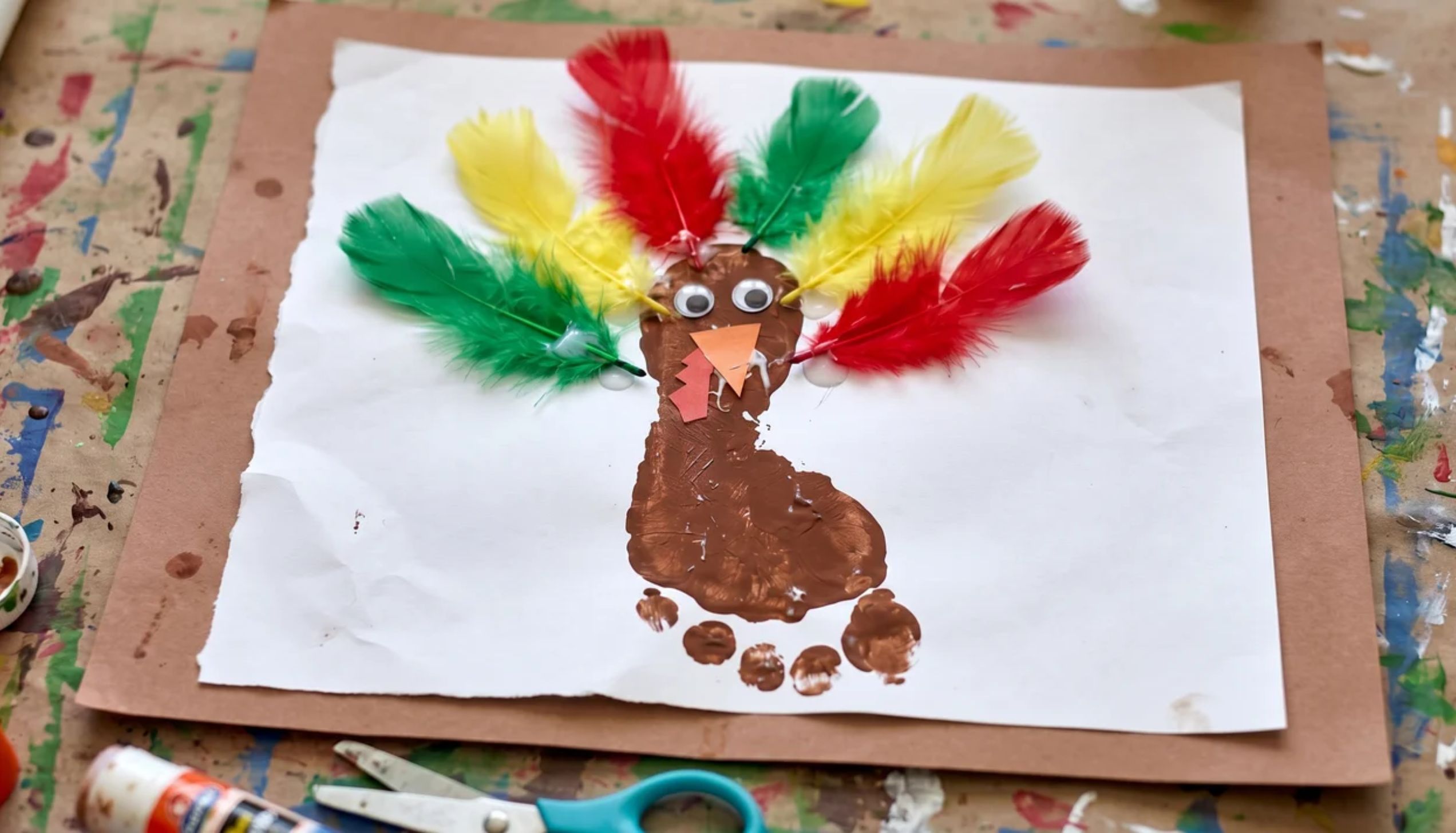 Toddler footprint turkey art on white paper with colorful drawn feathers as a easy Thanksgiving crafts for toddlers